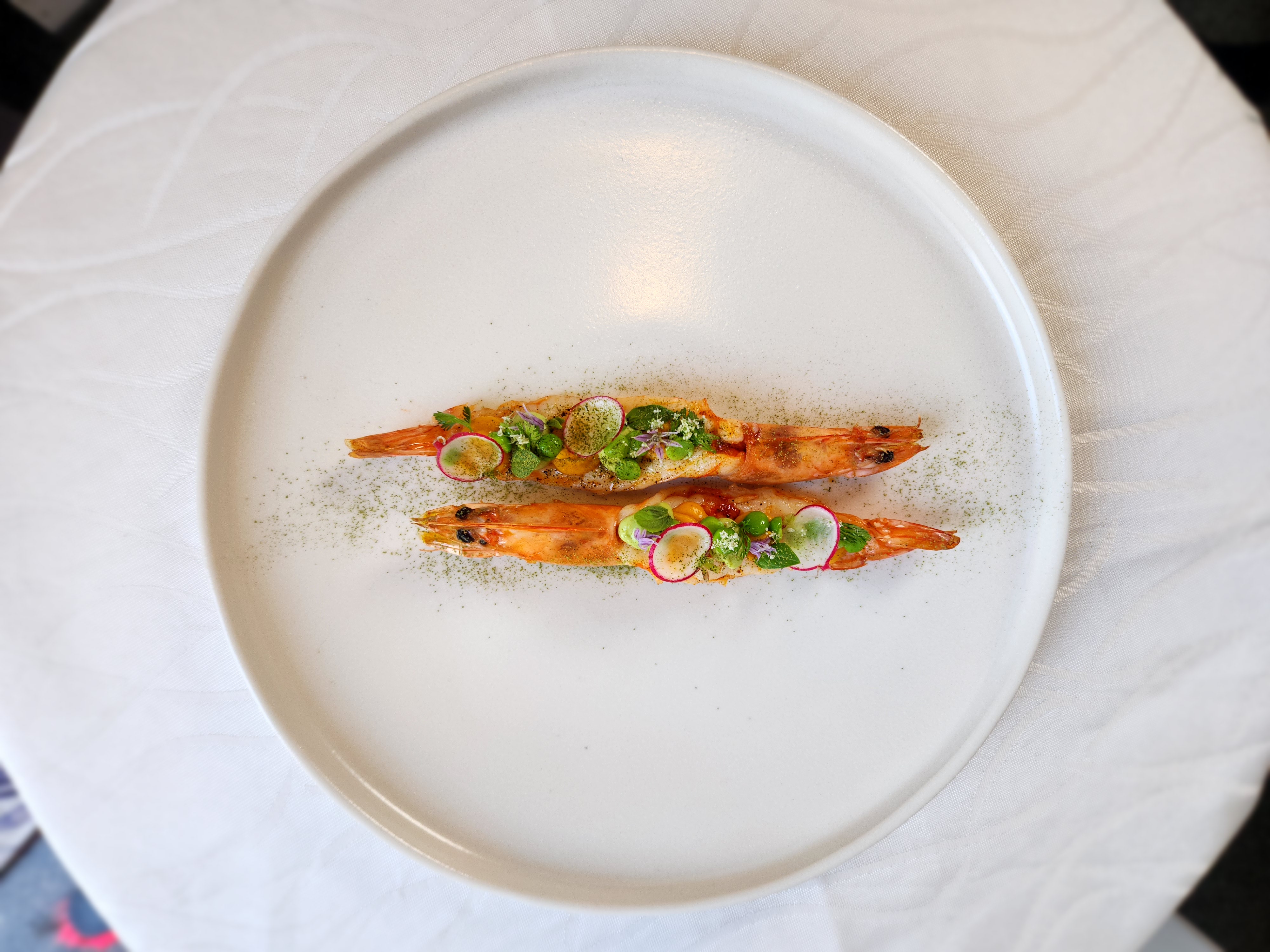Whole prawns dusted with herb powder, dressed with radish, peas, and edible flowers